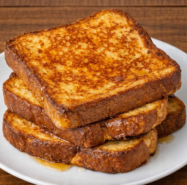 Three slices of brioche french toast stacked on a white plate.