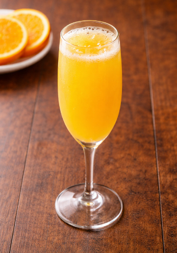 A mimosa in a champagne flute on a wood table